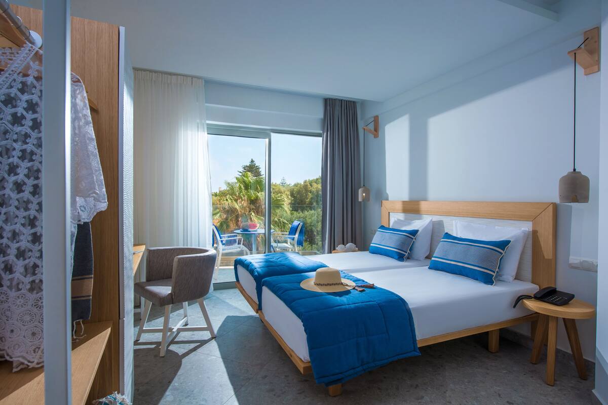 Une chambre d’hôtel avec un grand lit, deux tables de chevet, une chaise et une vue sur l’extérieur.