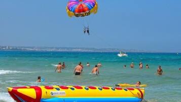 A beach scene with people swimming and parasailing.