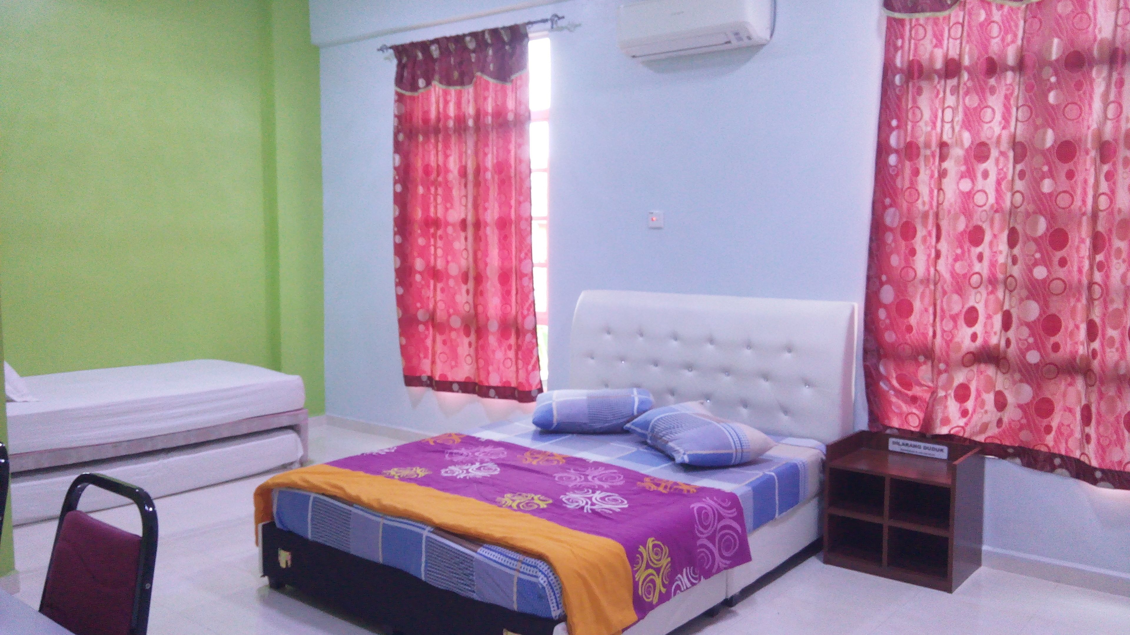 A bedroom with a bed, a chair, a bedside table, and curtains.