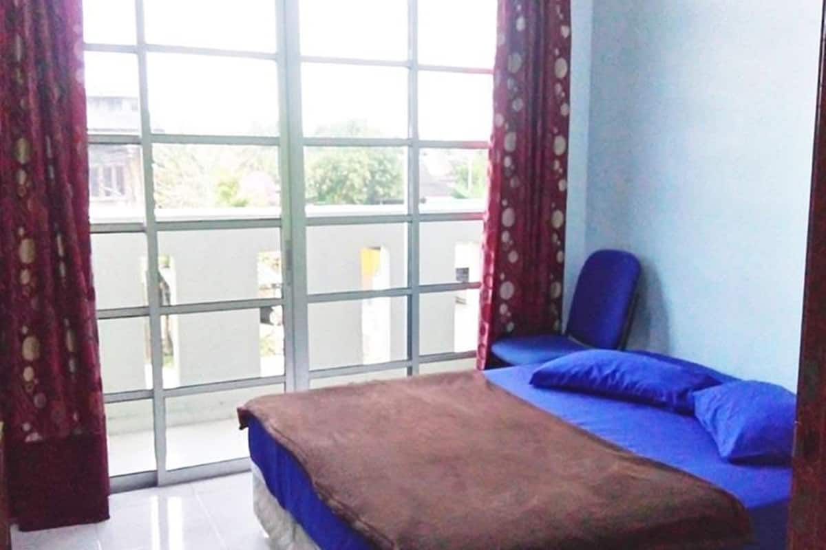 Une chambre à coucher avec un lit, une chaise et une vue dégagée sur l’extérieur grâce à une grande fenêtre.