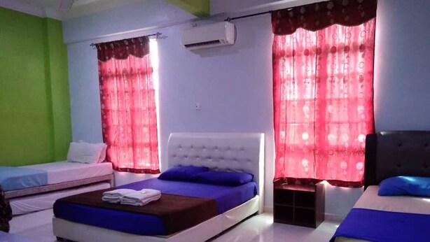 A bedroom with two beds, a window with red curtains, an air conditioning unit, and a small table.