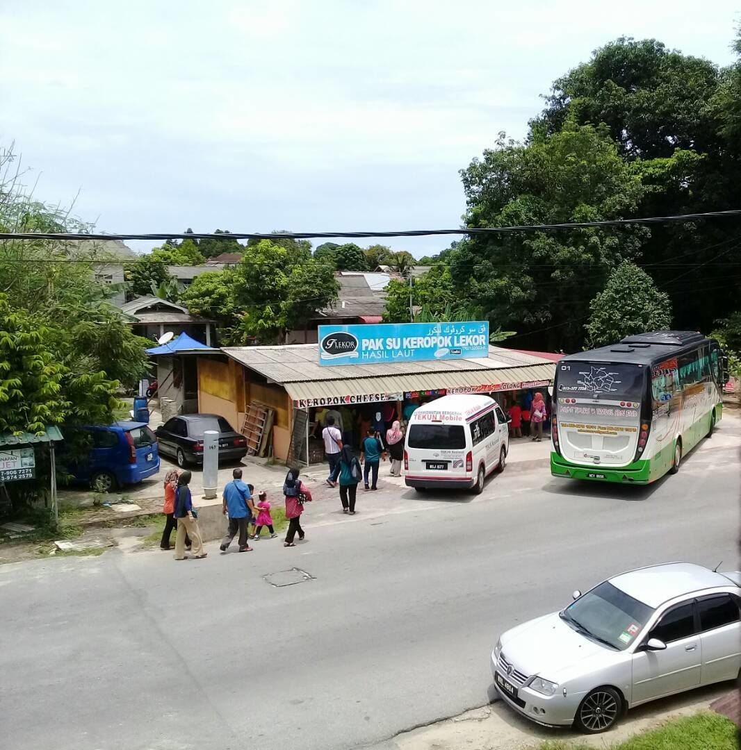 A street scene with a building labeled 'PAK SU KEROPOK LEKOR HASIL LAUT' and a bus parked nearby.