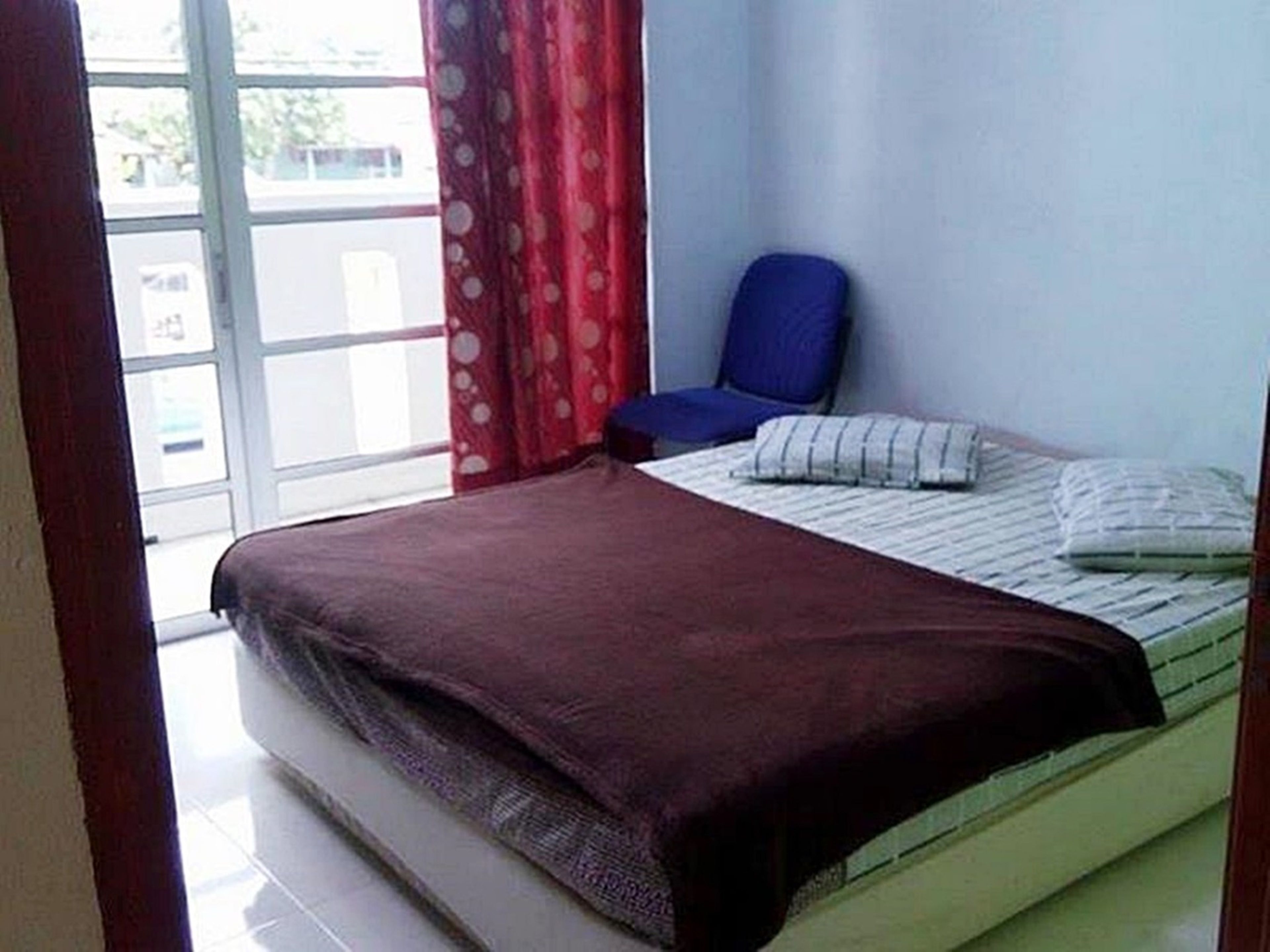 A room with a bed, a chair, and a window with curtains.
