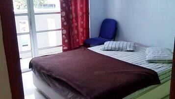 A room with a bed, a chair, and a window with curtains.