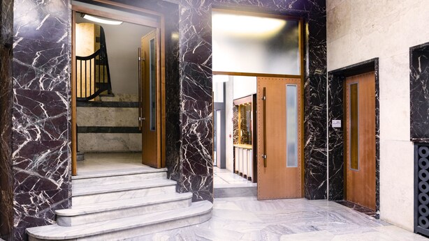 A marble-floored lobby with a staircase leading to an upper level, wooden doors, and a modern elevator. - BC MAISON bed&cafe Milano (Milan)