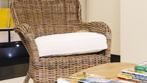 A wicker chair with a white cushion, a bookshelf with books, and a table with magazines. - BC MAISON bed&cafe Milano (Milan)