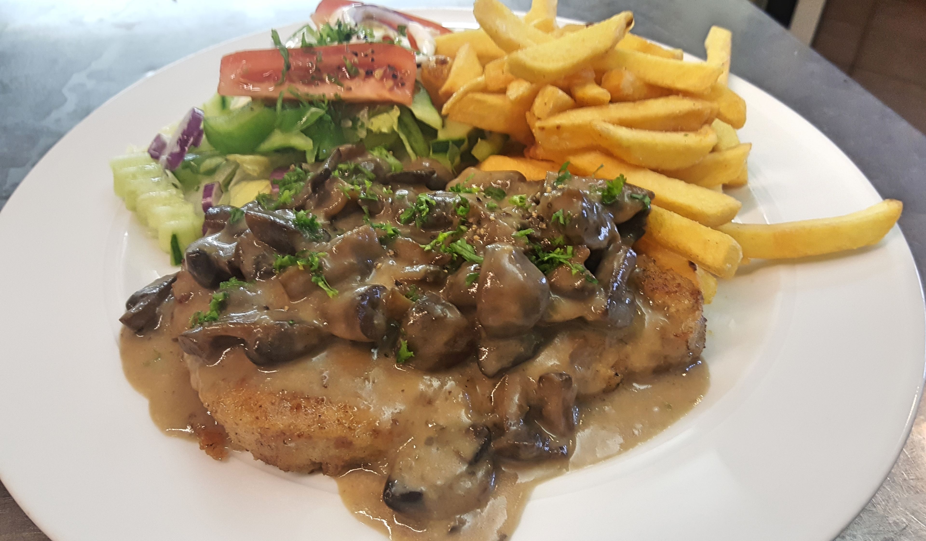 En tallerken med kødret, pommes frites og salat.