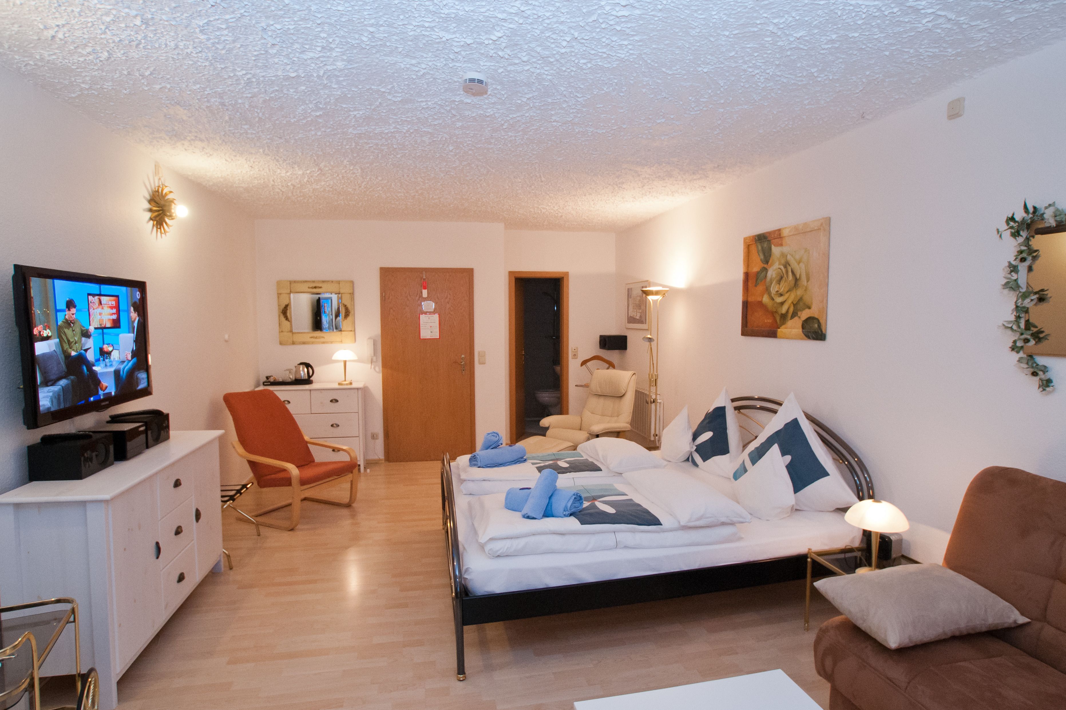 Habitació d'hotel amb llit, televisió, cadira, escriptori i porta.