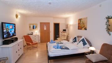 Habitació d'hotel amb llit, televisió, cadira, escriptori i porta.