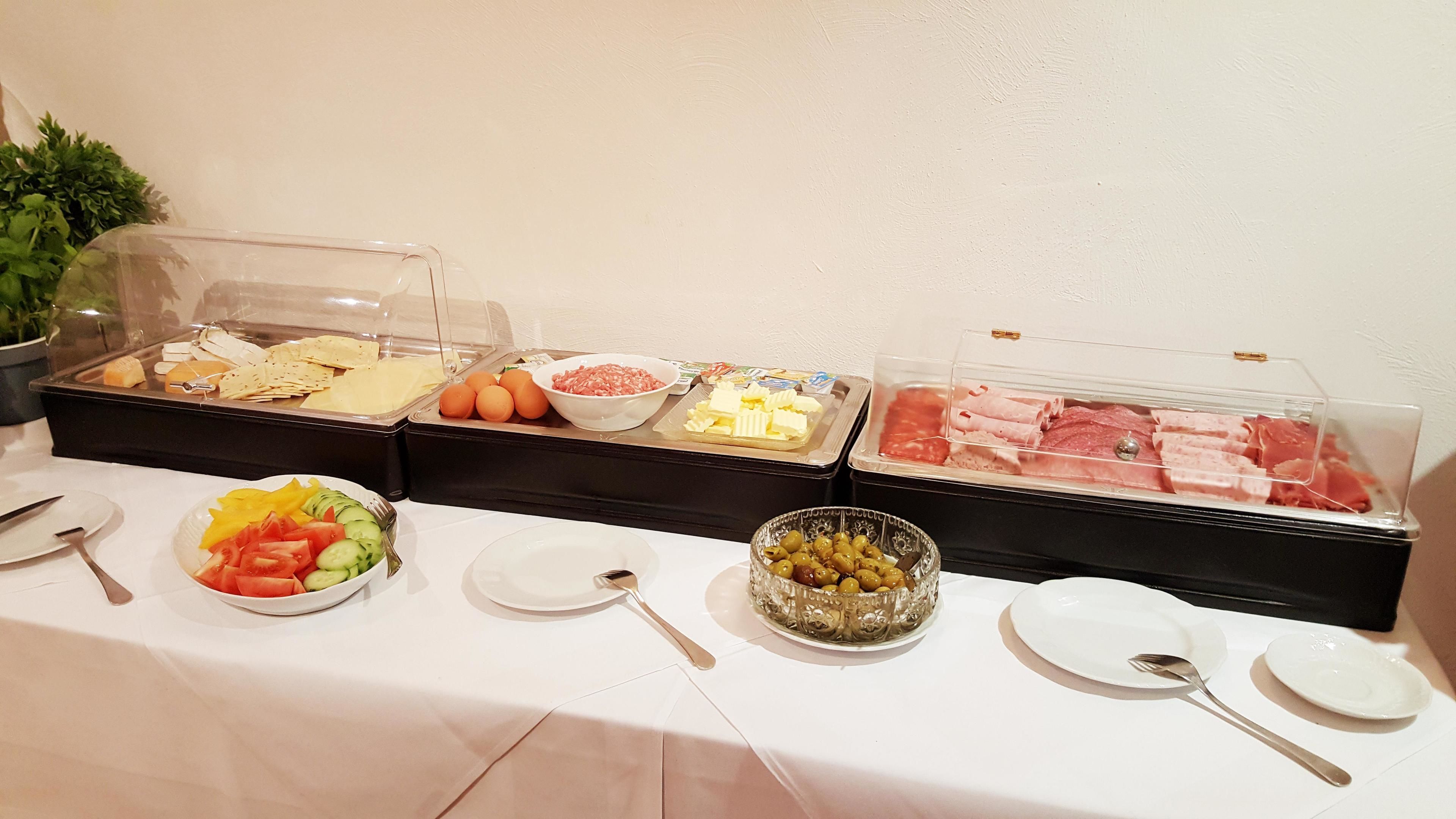 A buffet with various food items including fruits, cheeses, meats, and olives.