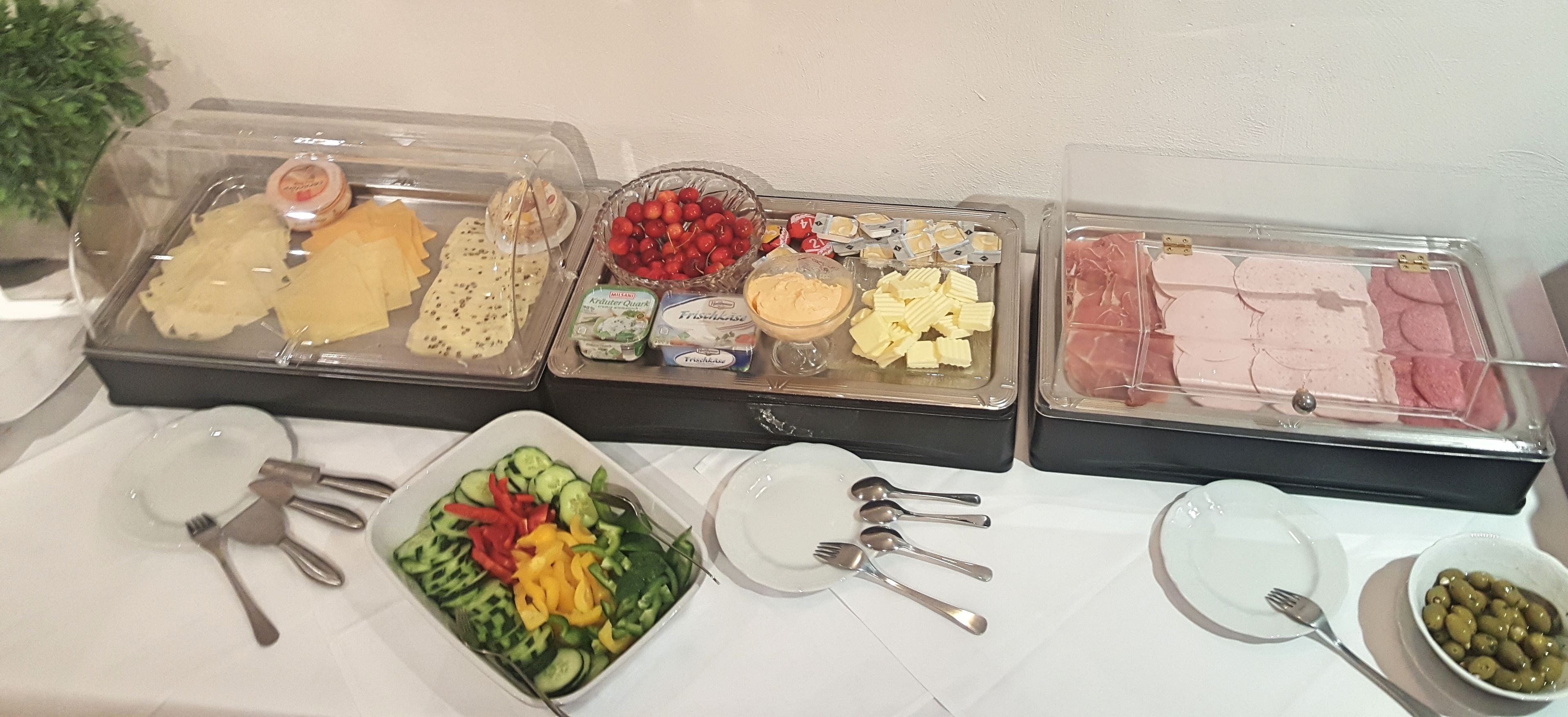 Un bufé con diversas opciones de comida, como frutas, quesos y embutidos.