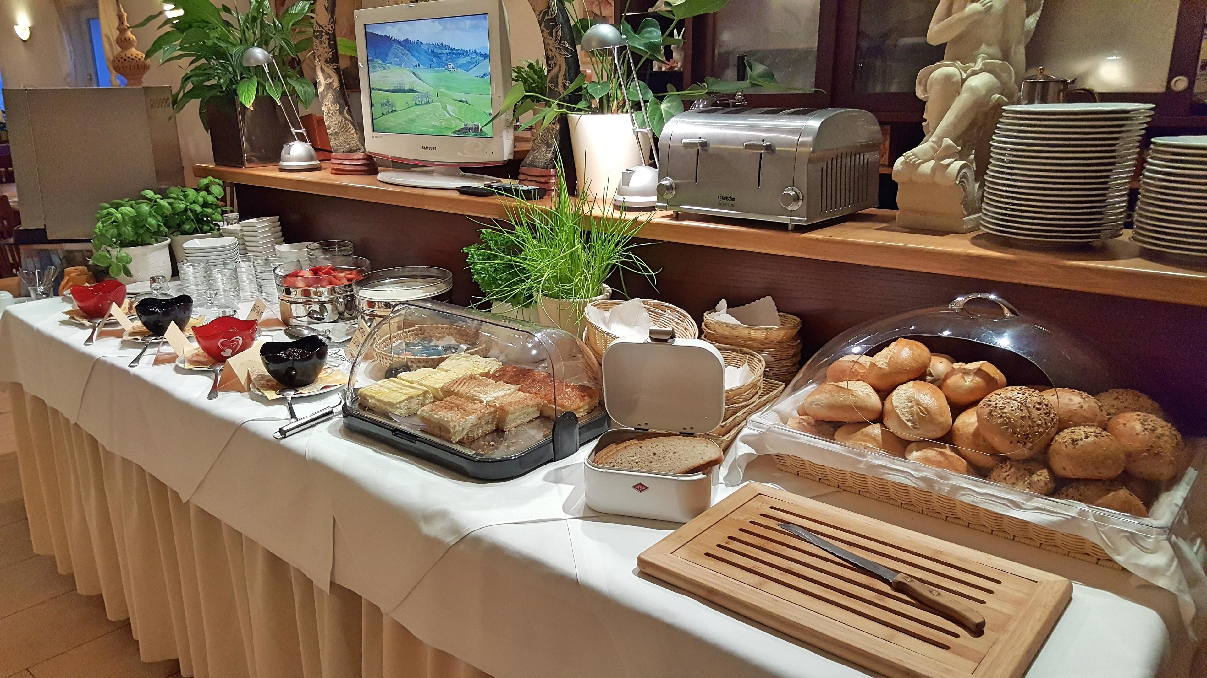 Una mesa con una variedad de alimentos en estilo bufé, un tostador y un monitor de computadora.