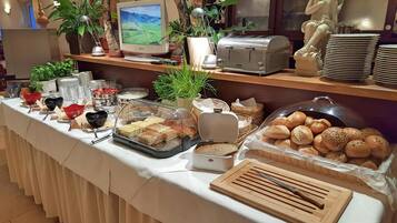 Una mesa con una variedad de alimentos en estilo bufé, un tostador y un monitor de computadora.