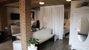 A modern living room with a white sofa, a brick column, a white cabinet, and a large mirror.