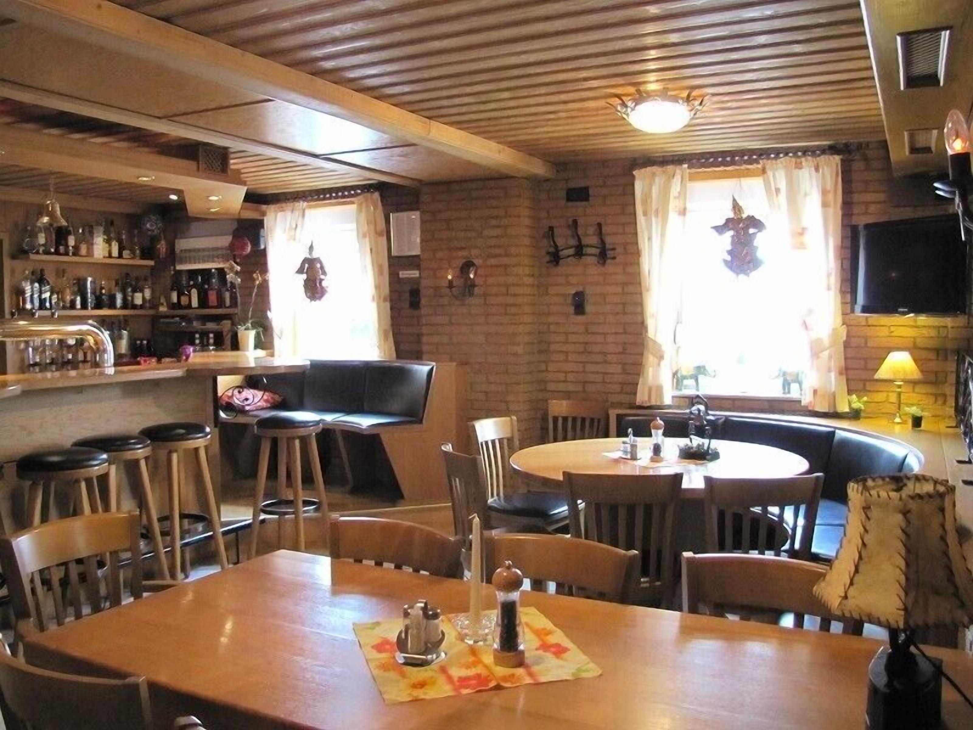 A cozy restaurant with a bar area, wooden furniture, and brick walls.