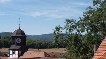 A building with a clock tower, surrounded by trees and hills.
