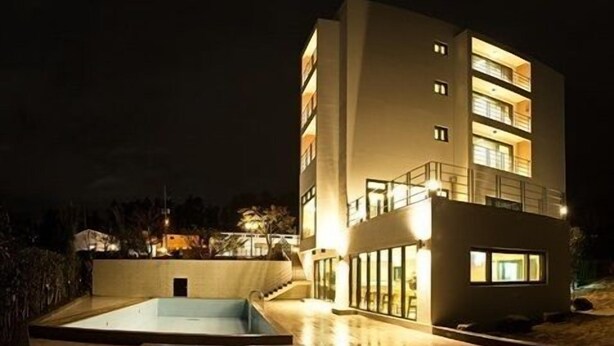 A modern multi-story building with a pool area. - Suave Hotel (Seogwipo)