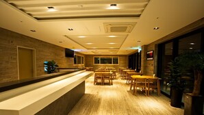 A hotel lobby with a reception desk, wooden flooring, and multiple seating areas. - Suave Hotel (Seogwipo)