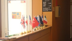A reception desk with flags of various countries and a sign indicating room rates. - Fountain Square Hotel (Baku)