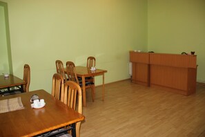 Un espace repas avec une table et des chaises en bois, un buffet et un mur de couleur vert clair.