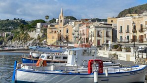 A harbor with boats docked, a church, and buildings in the background. - Mamamia Guesthouse (Lipari)