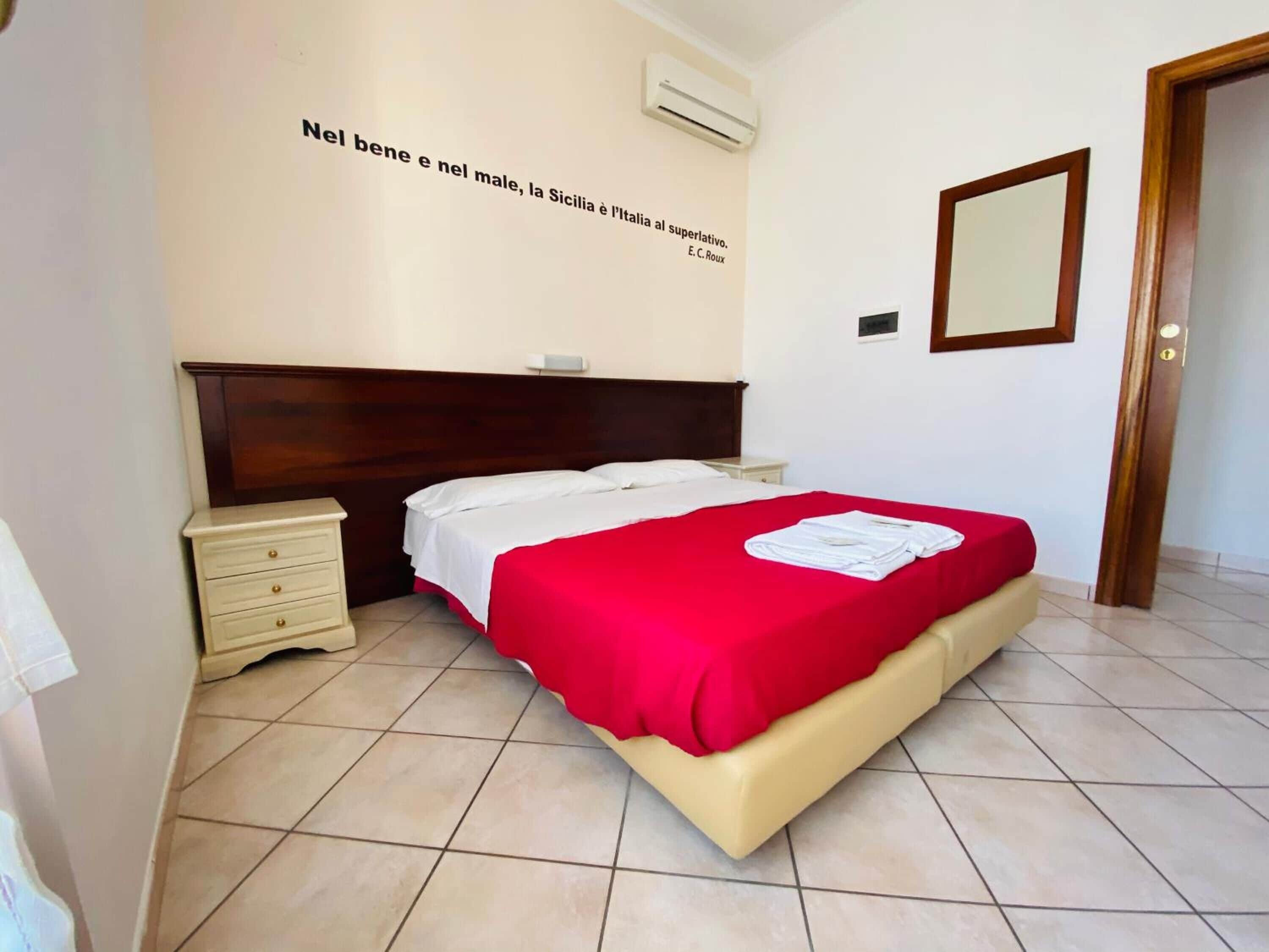 Una habitación de hotel con una cama, una mesita de noche, un aire acondicionado de pared y una puerta.