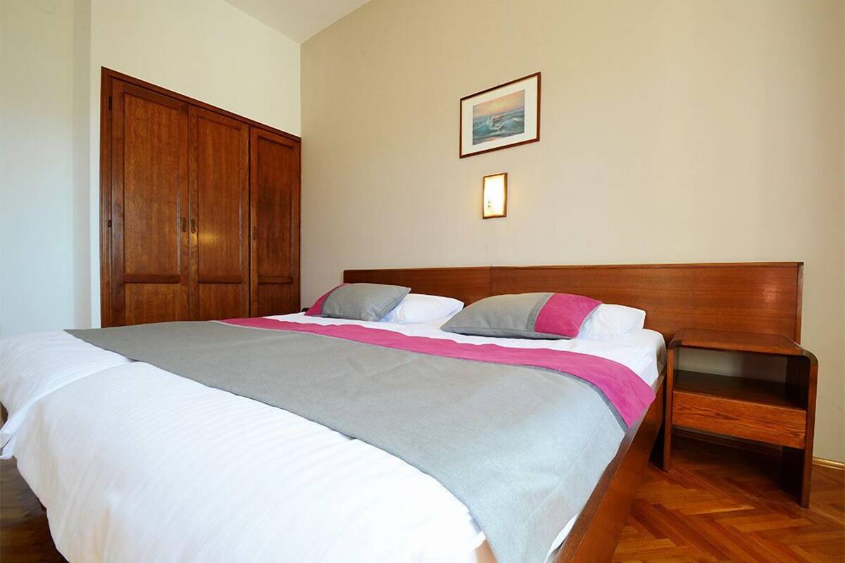 Un dormitorio con una cama grande, un armario de madera y una mesita de noche.