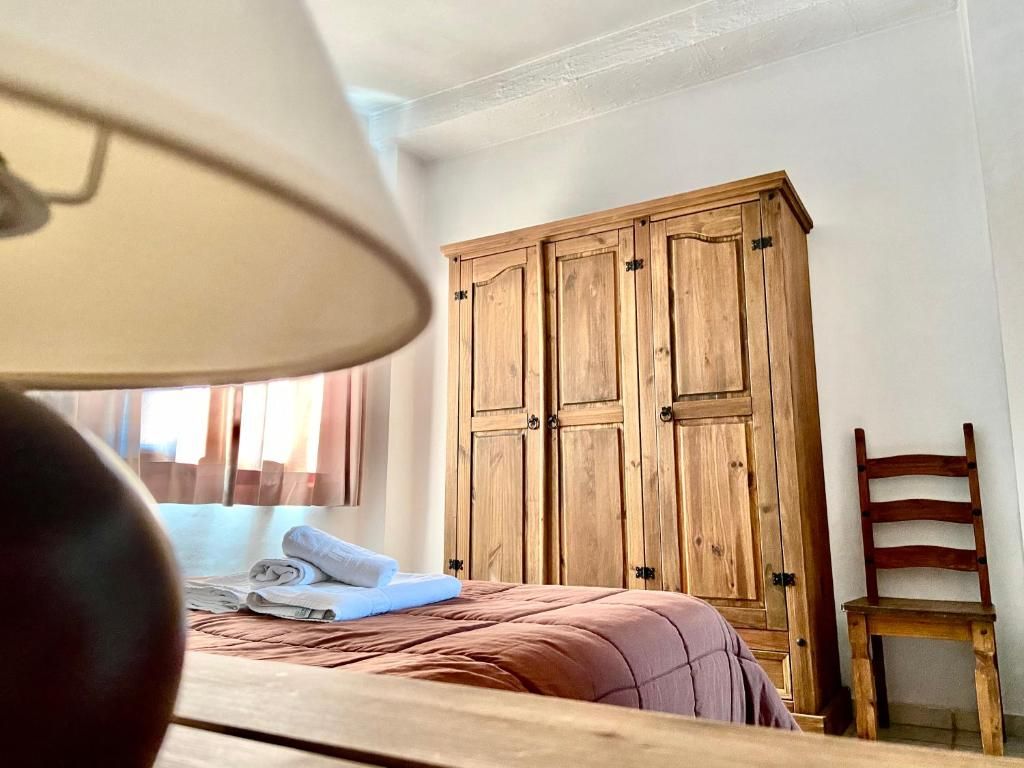 Una habitación con una cama, un armario de madera y una silla.