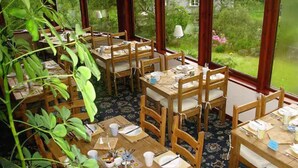 A dining area with wooden tables and chairs, arranged in a semi-circle.