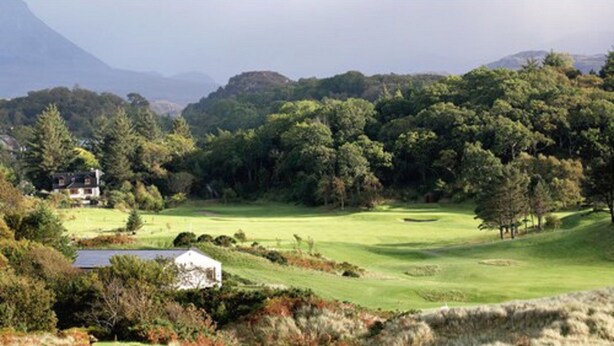 A golf course with a house in the foreground and a mountain in the background.