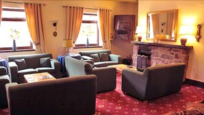 A cozy living room with multiple sofas, a fireplace, and a patterned carpet.