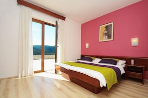 A bedroom with a bed, a nightstand, a painting, and a view through a sliding glass door. - House Adrijana (Labin)
