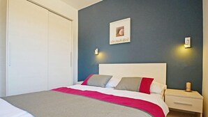 Un dormitorio con cama, mesita de noche y un cuadro en la pared.