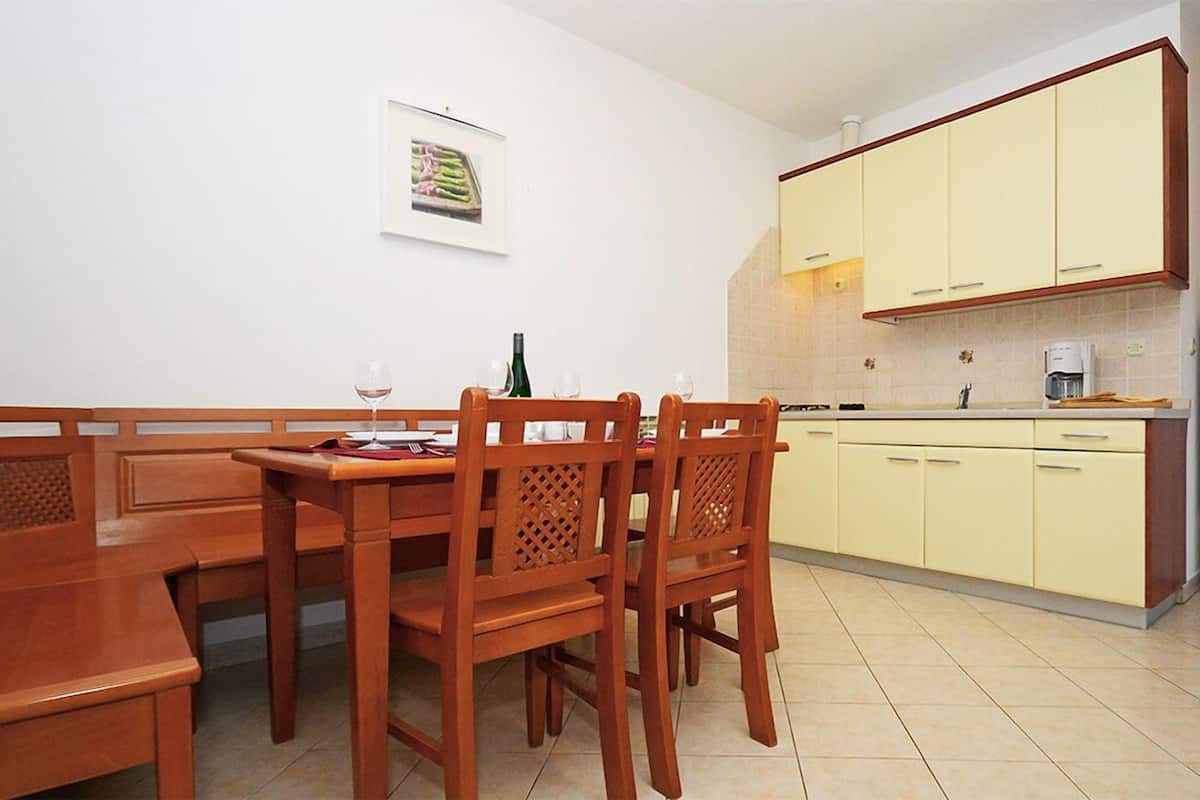 Ein Essbereich mit Holztisch und Stühlen, einer Weinflasche und einem gerahmten Bild an der Wand.