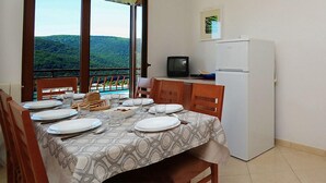Un comedor con una mesa preparada para cuatro, un televisor y un refrigerador.