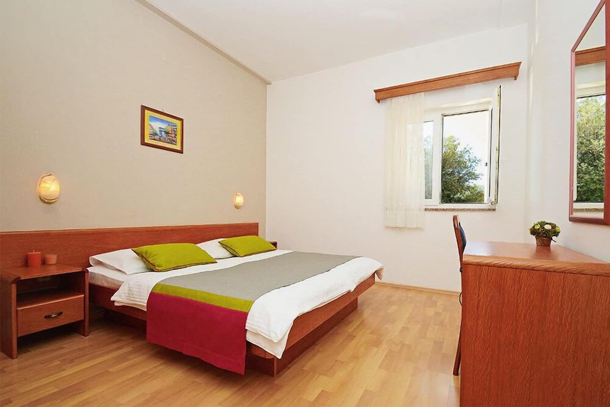 Ein Schlafzimmer mit einem hölzernen Bett, einem Nachttisch und einem Schreibtisch mit Stuhl.