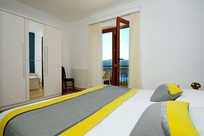 A hotel room with a bed, a wardrobe, a chair, and a balcony with a view.