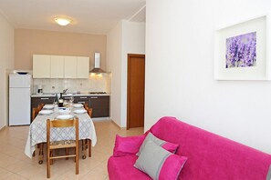 A compact living space with a dining area, kitchenette, and a pink sofa. - House Adrijana (Labin)