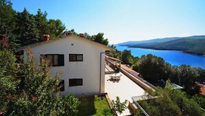 Un edificio blanco con balcón que da a un lago y montañas.