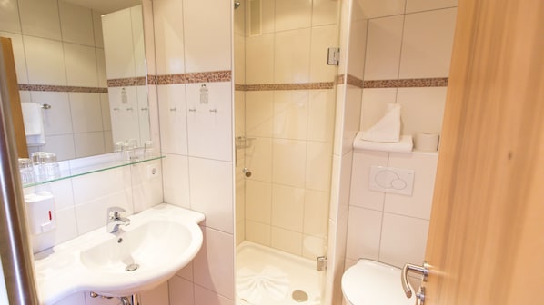 Un baño con lavamanos, espejo, ducha e inodoro.