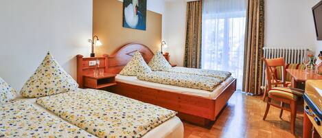 Habitación de hotel con dos camas, una zona de comedor y un cuadro en la pared.