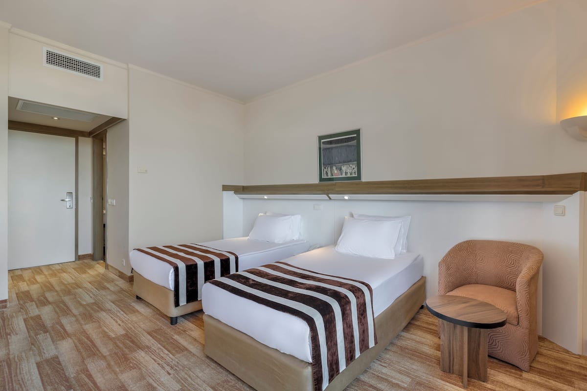 A hotel room with two beds, a small round table, and a chair.