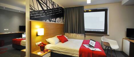 Une chambre d’hôtel moderne équipée d’un grand lit, d’un bureau, d’une chaise et d’un téléviseur.