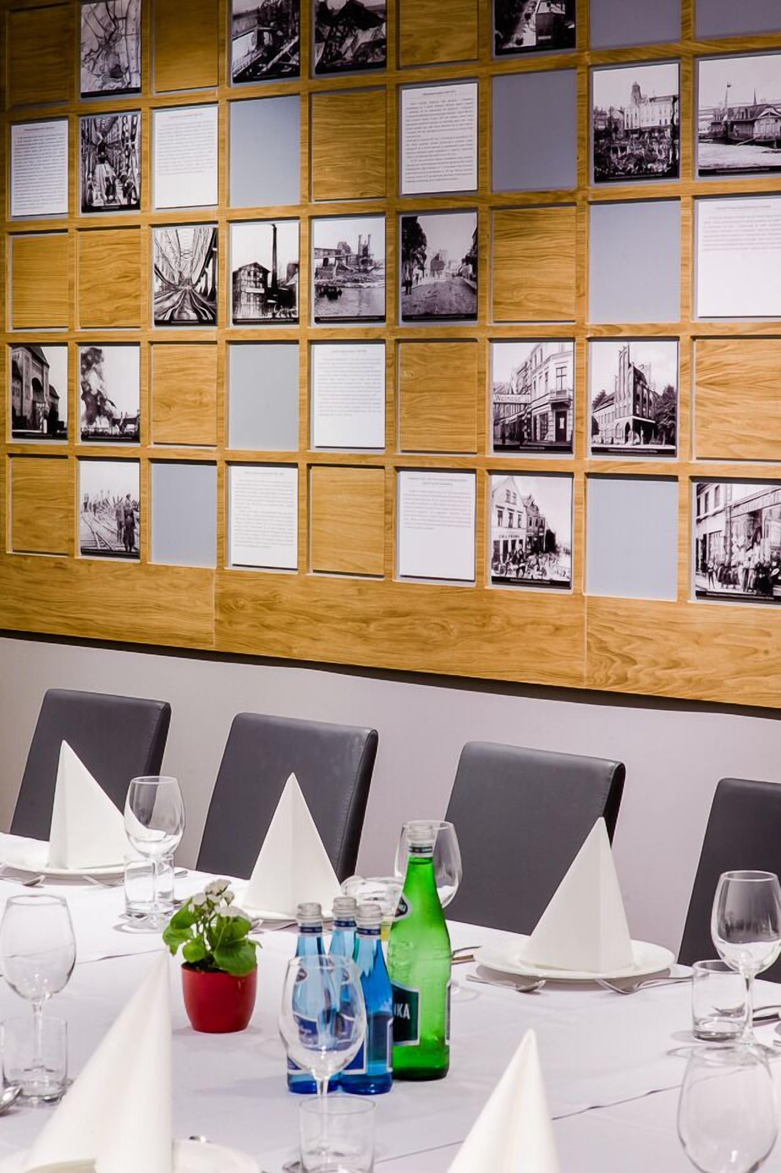 Een vergaderzaal met een houten paneelwand waarop zwart-witfoto’s staan.