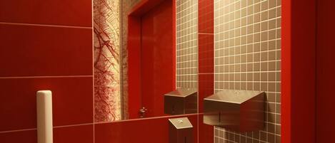 A modern bathroom with red tiled walls, a white sink, and a mirror above it.