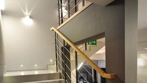 A modern staircase with a wooden handrail and metal balusters, leading to an upper floor.