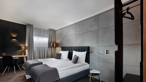 A modern hotel room with a large bed, two bedside tables, a desk, and a chair.