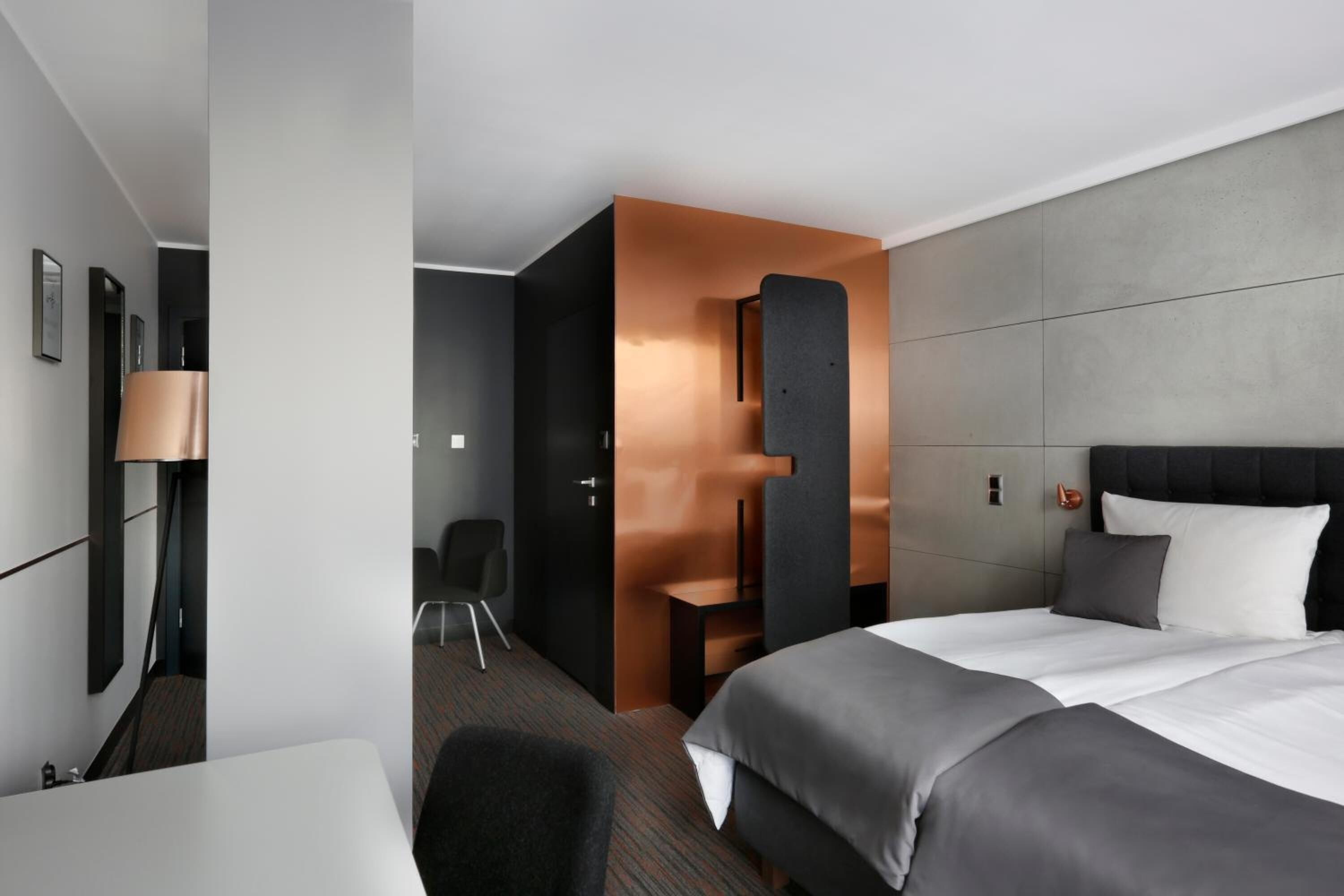 A modern hotel room with a large bed, a desk, and a seating area.