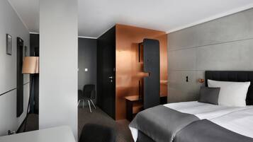 A modern hotel room with a large bed, a desk, and a seating area.