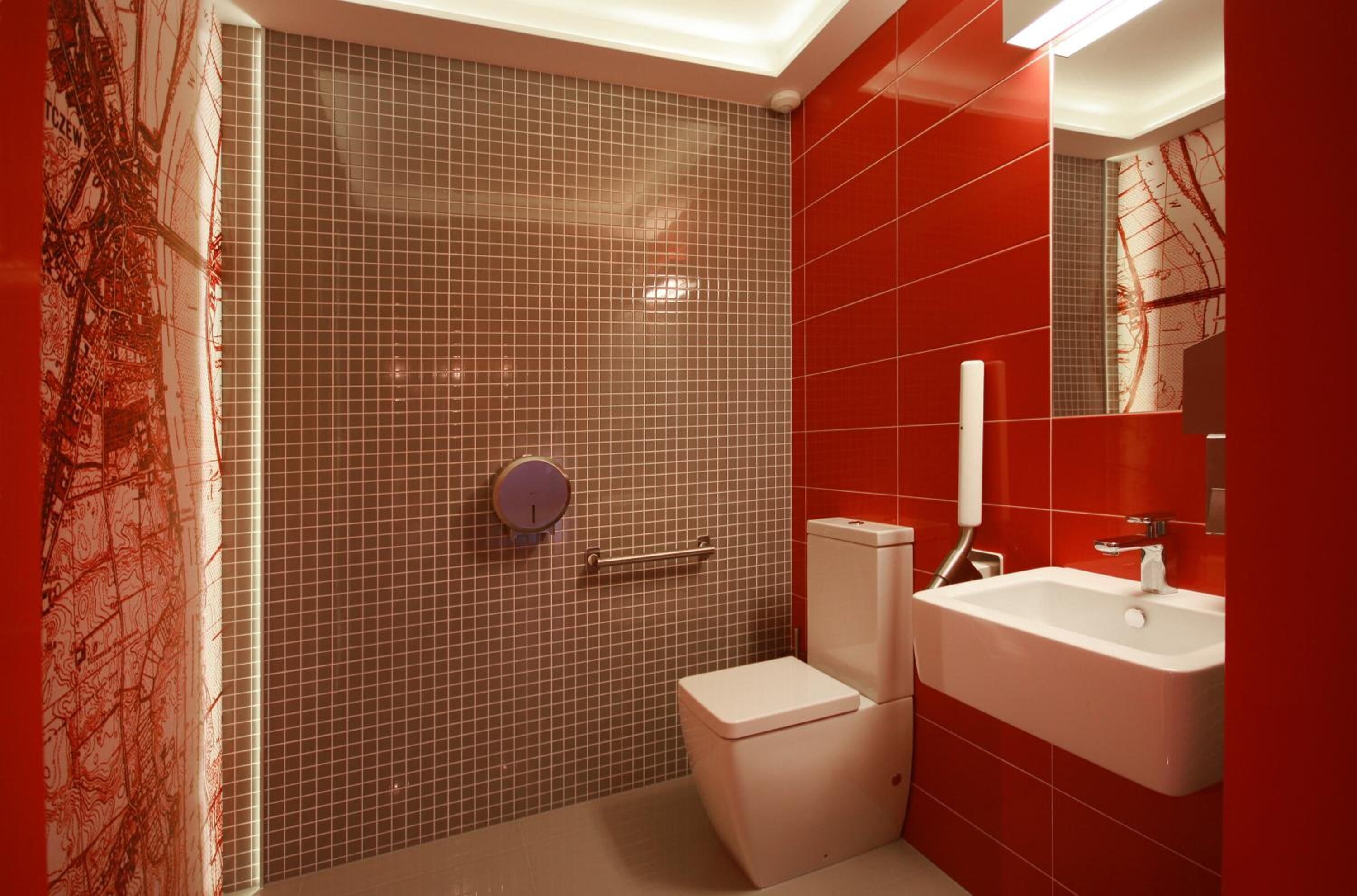 A bathroom with a red tiled wall, a white sink, and a toilet.